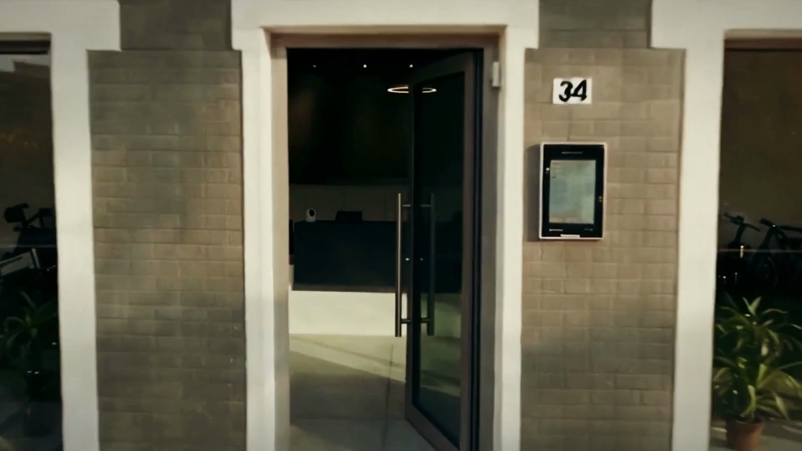 L'ingresso della sede NEXTTOSKIN al civico 34 di Via Gandhi a Modena, con la porta a vetri aperta e biciclette elettriche dietro le vetrine